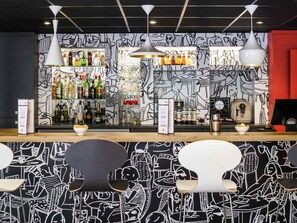 A bar with a black and white mural, shelves of liquor bottles, and modern pendant lighting. - ibis Paris Pont De Suresnes (Suresnes)