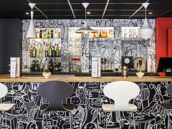 A bar with a black and white mural, shelves of liquor bottles, and modern pendant lighting. - ibis Paris Pont De Suresnes (Suresnes)