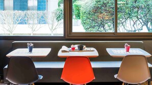 A seating area with a bench, three chairs, and tables. - ibis Paris Pont De Suresnes (Suresnes)