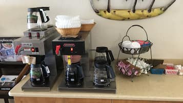 Un coin café équipé de plusieurs machines à café, d’un panier et d’un plateau contenant des tasses et des couverts.