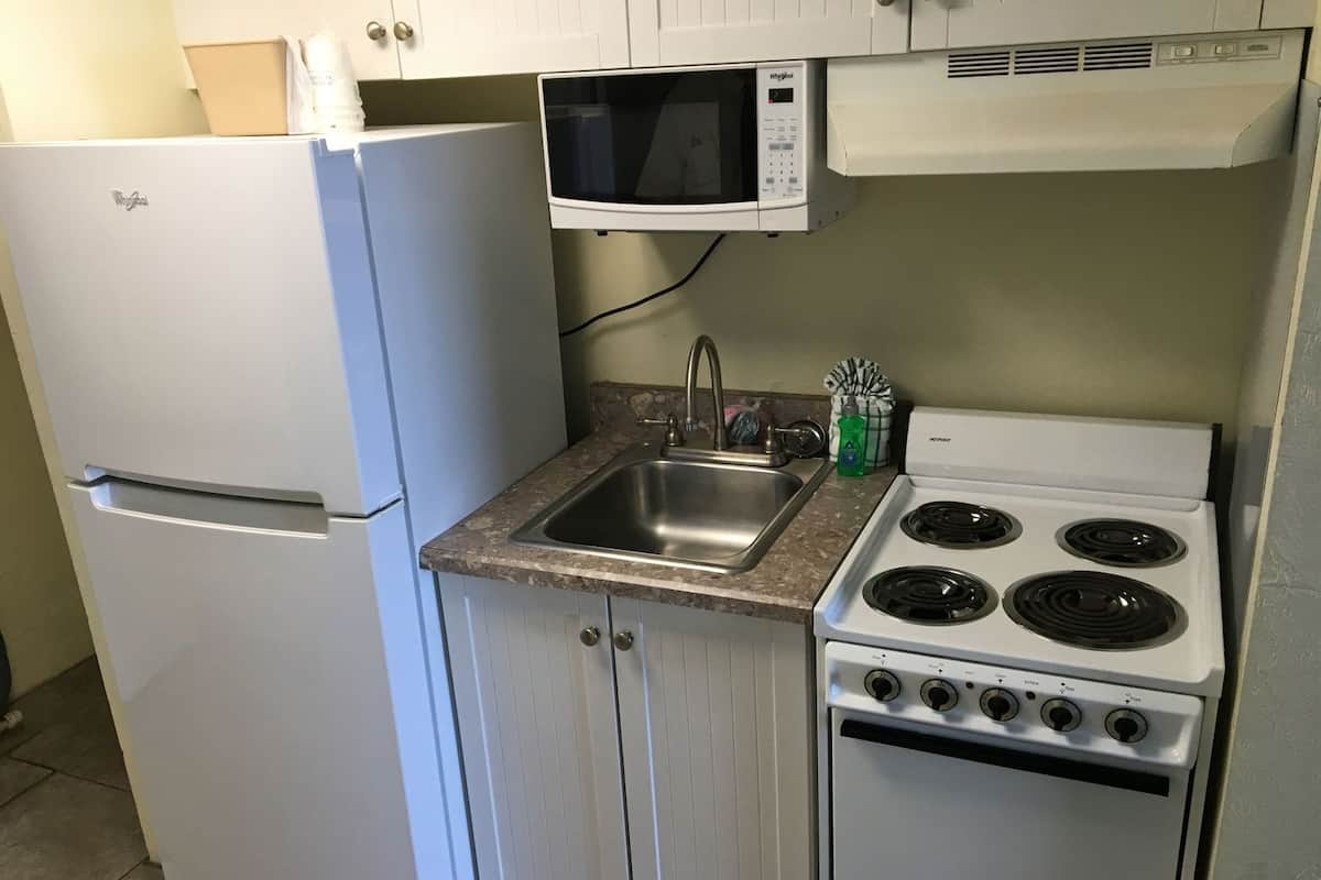 A compact kitchen with a refrigerator, microwave, sink, and stove.