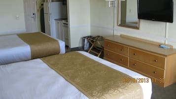 A hotel room with two beds, a dresser, a television, and a kitchenette.