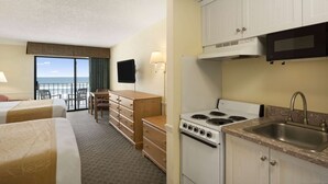 Hotelkamer met twee bedden, een kitchenette, een televisie, een balkon met uitzicht en een bureau met stoelen.