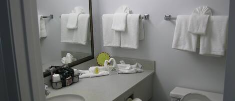 Un baño con lavamanos, espejo, toallero, inodoro y artículos de aseo.