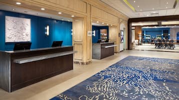 Welcome to our hotel lobby, featuring a reception desk and bar area with comfortable seating and a large screen.