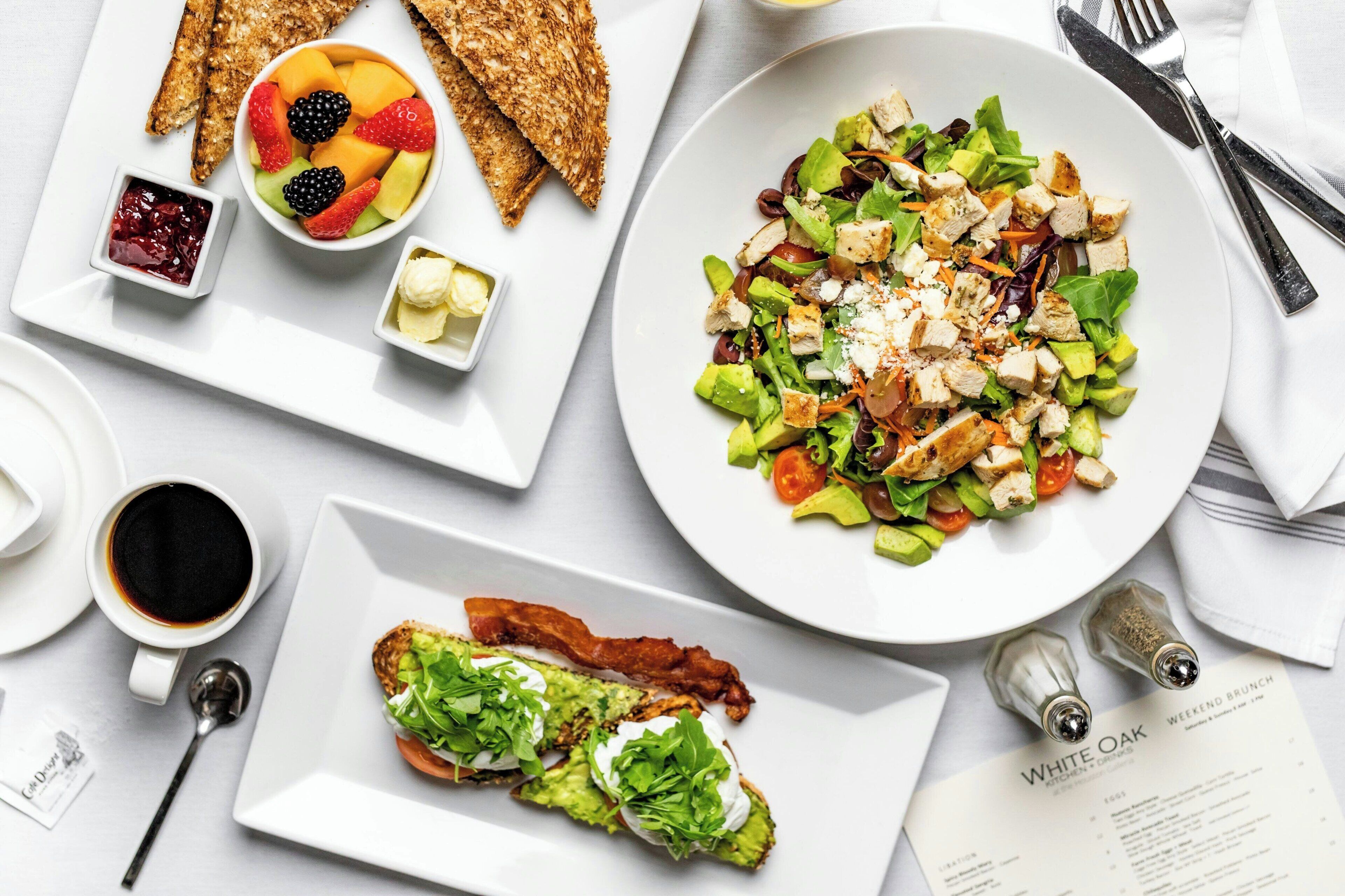 A breakfast setting with toast, fruit, a salad, and a menu.