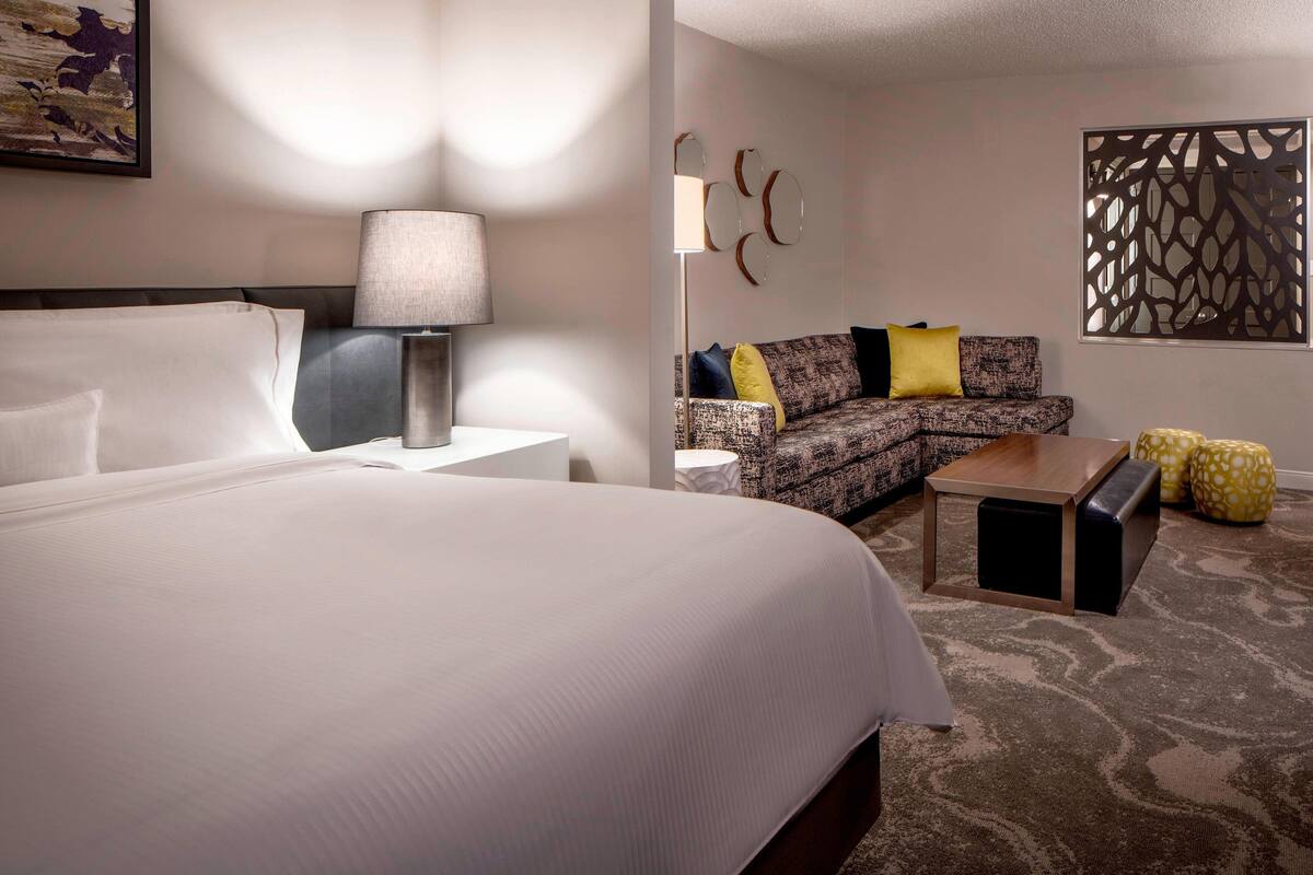 Een hotelkamer met een groot bed, een bank, een salontafel en een decoratieres.