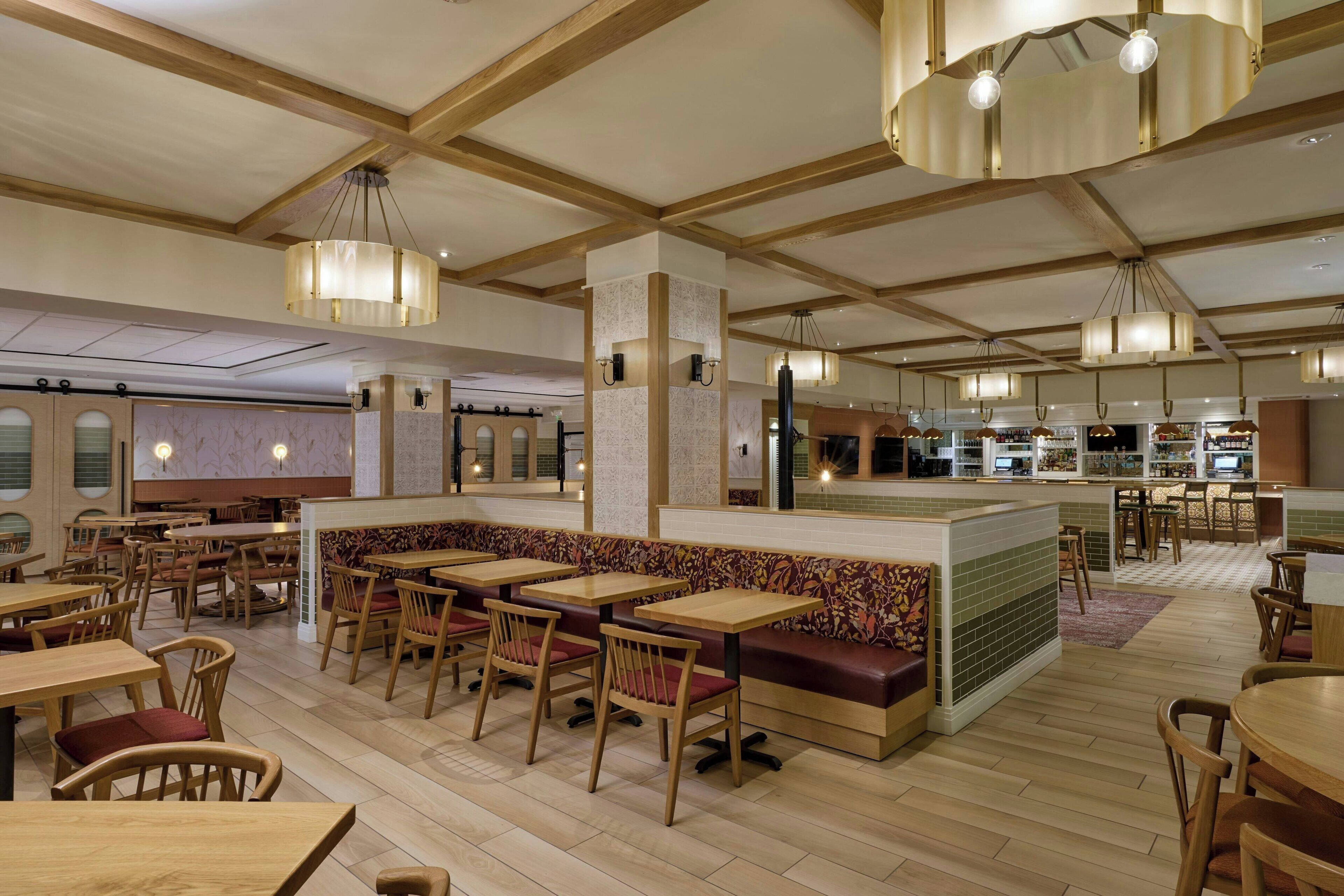 Un restaurant avec des tables et des chaises en bois, un comptoir et des lampes suspendues.