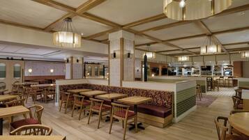 Un restaurant avec des tables et des chaises en bois, un comptoir et des lampes suspendues.