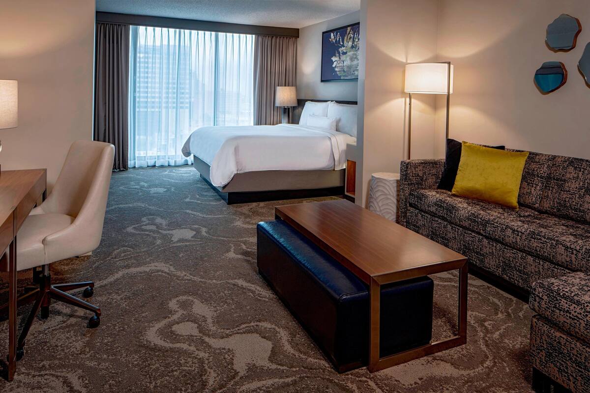 Een hotelkamer met een groot bed, een bank, een bureau en een lamp.