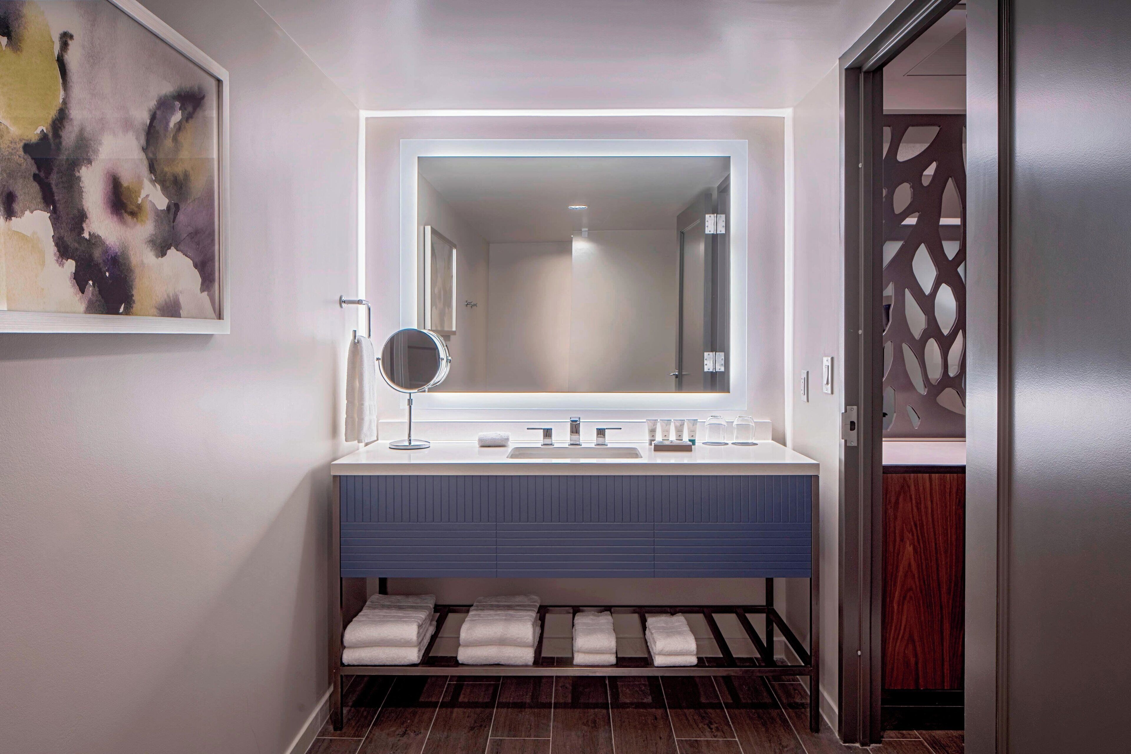 A modern bathroom with a large mirror, two sinks, and a towel rack.
