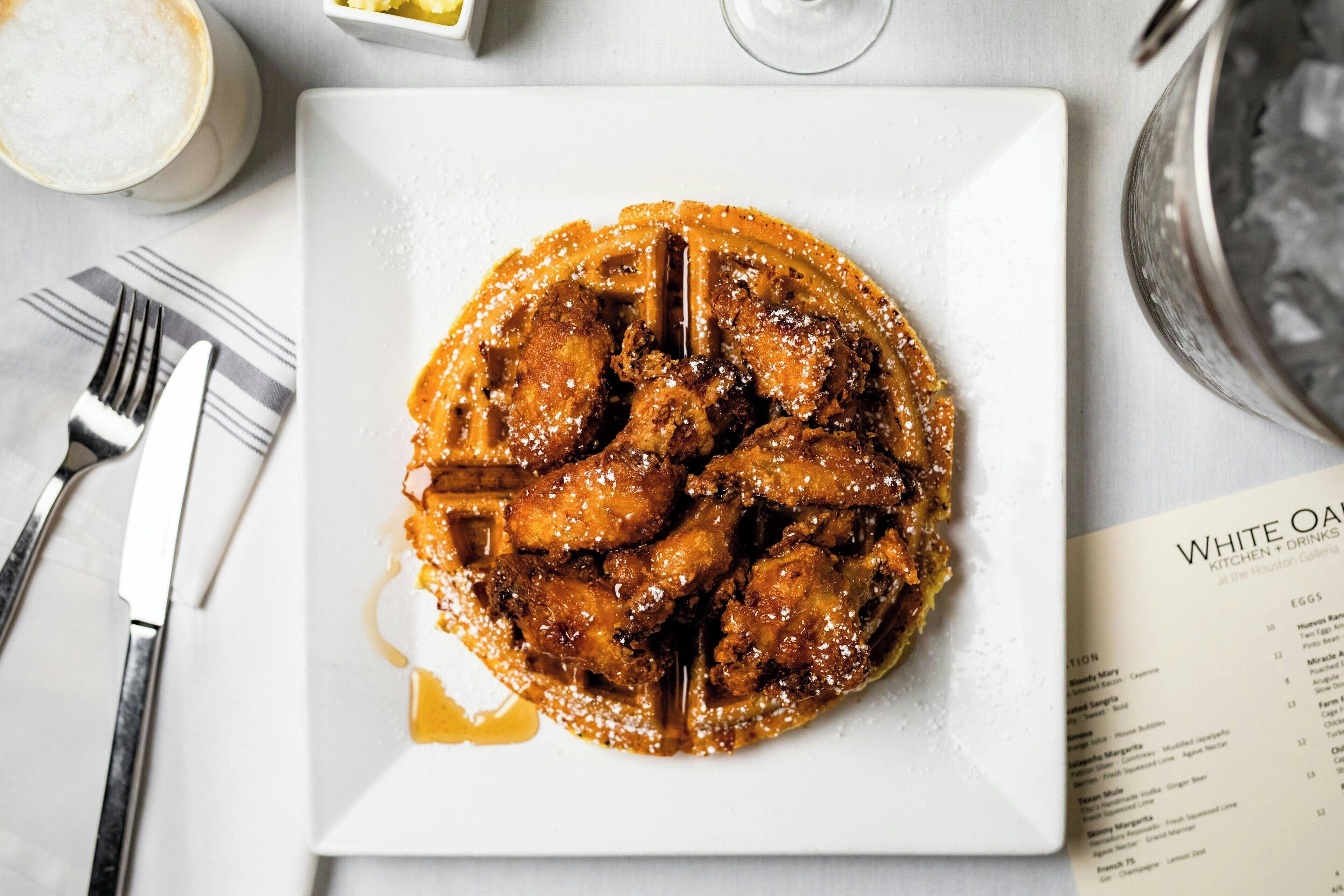A plate of fried chicken with syrup and sugar on a white plate.