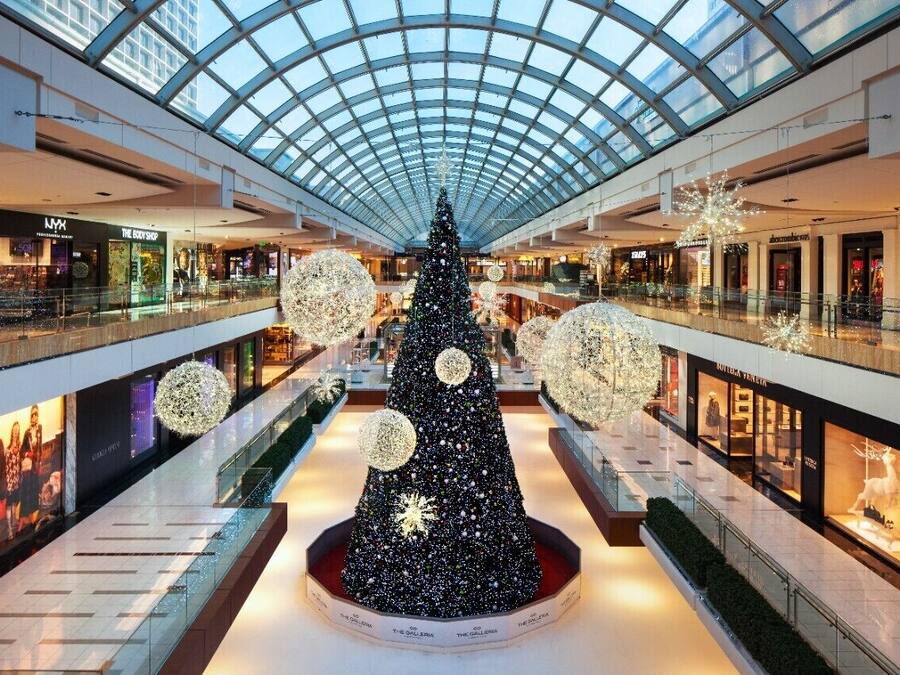 A shopping mall with a large Christmas tree in the center, surrounded by illuminated spherical decorations.