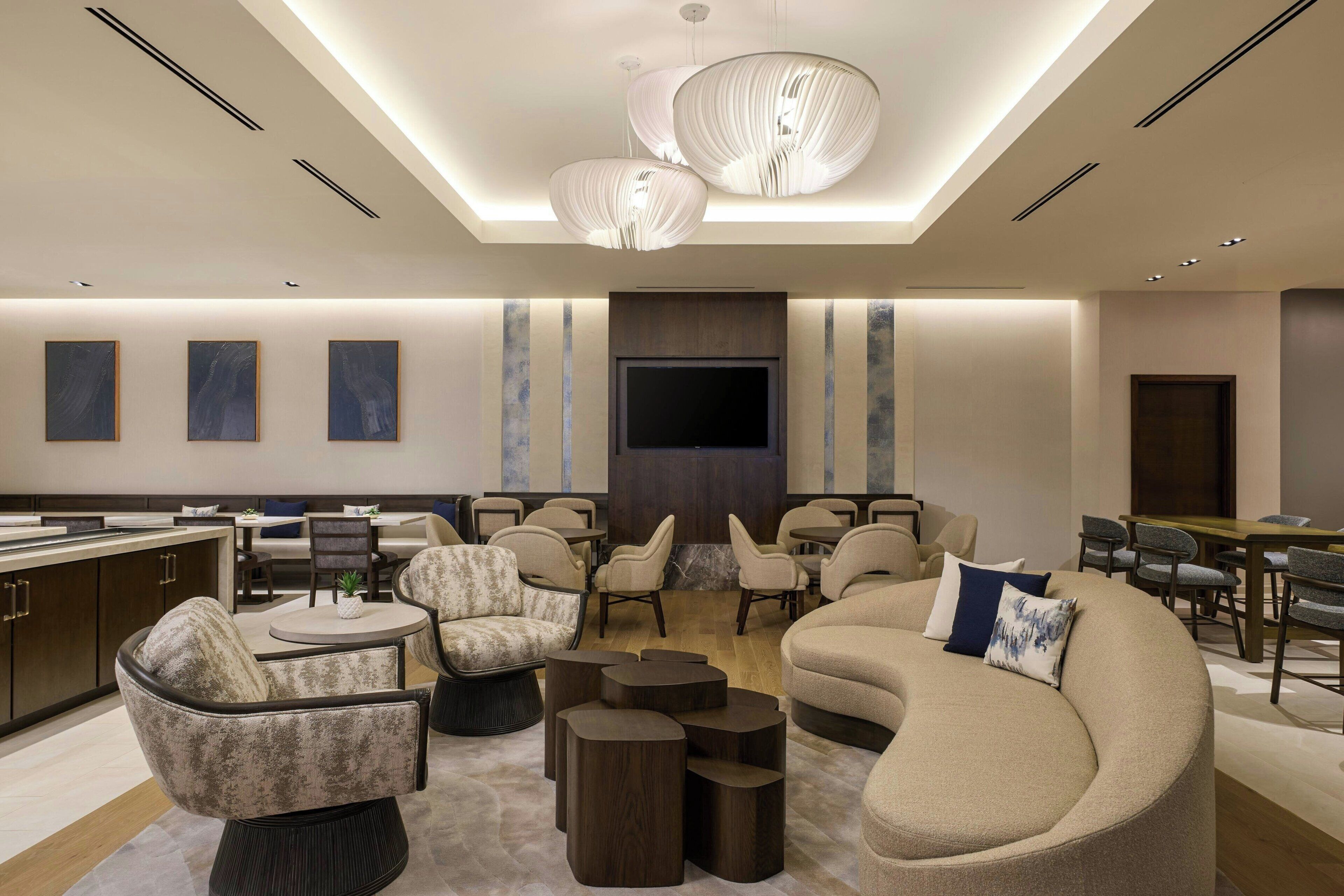 A modern lounge area with sofas, chairs, a TV, and a bar.
