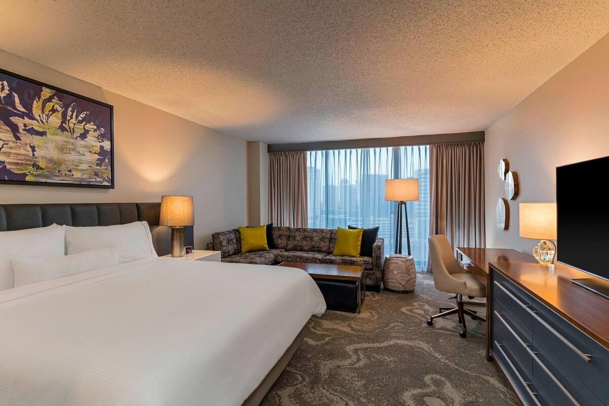 Een hotelkamer met een groot bed, een bank, een bureau en een televisie.