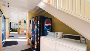 A laundry area with a washing machine, a dryer, and a vending machine with a Pepsi logo. - Rodeway Inn Augusta West - Fort Gordon (Augusta)
