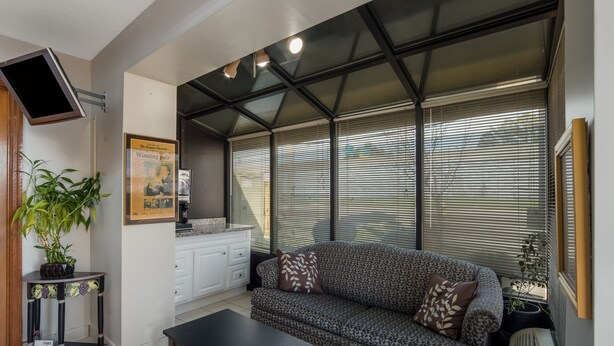A living room with a sofa, a coffee table, a TV, and a plant. - Rodeway Inn Augusta West - Fort Gordon (Augusta)