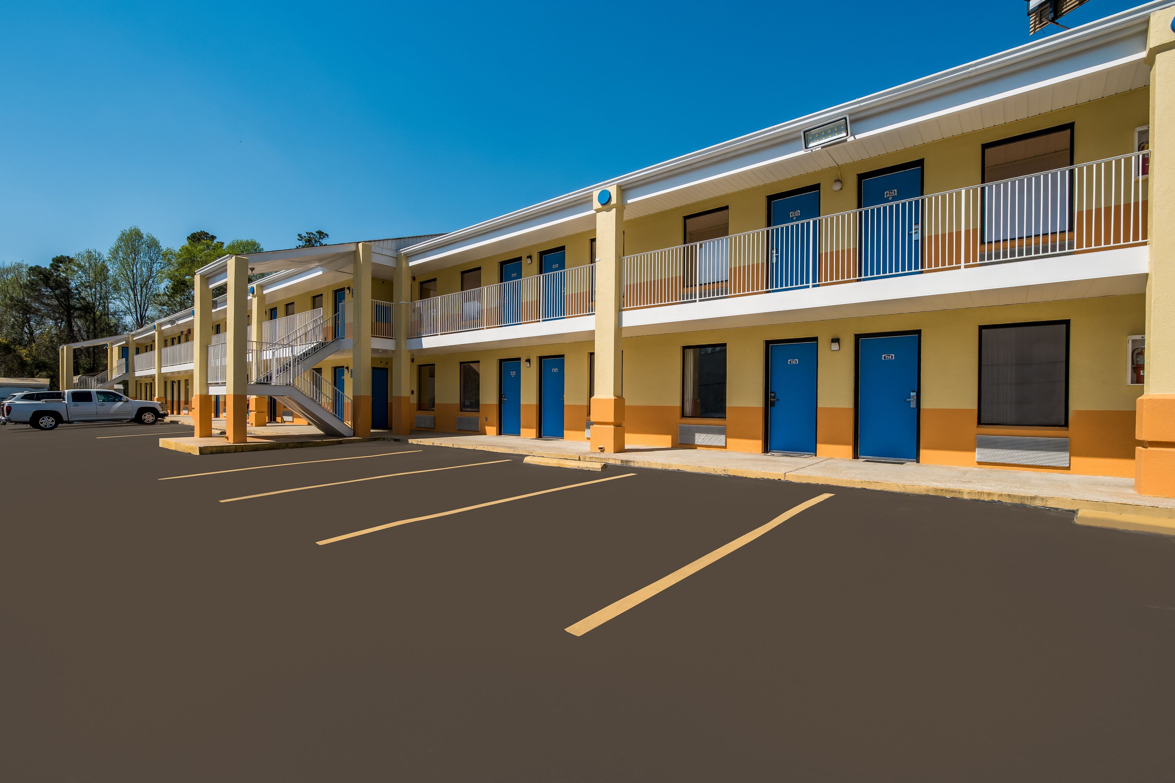 Un motel à plusieurs étages, doté de balcons et d’un parking.