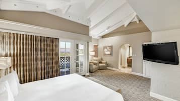 A hotel room with a large bed, a television, a sliding door to a balcony, and a carpeted floor.