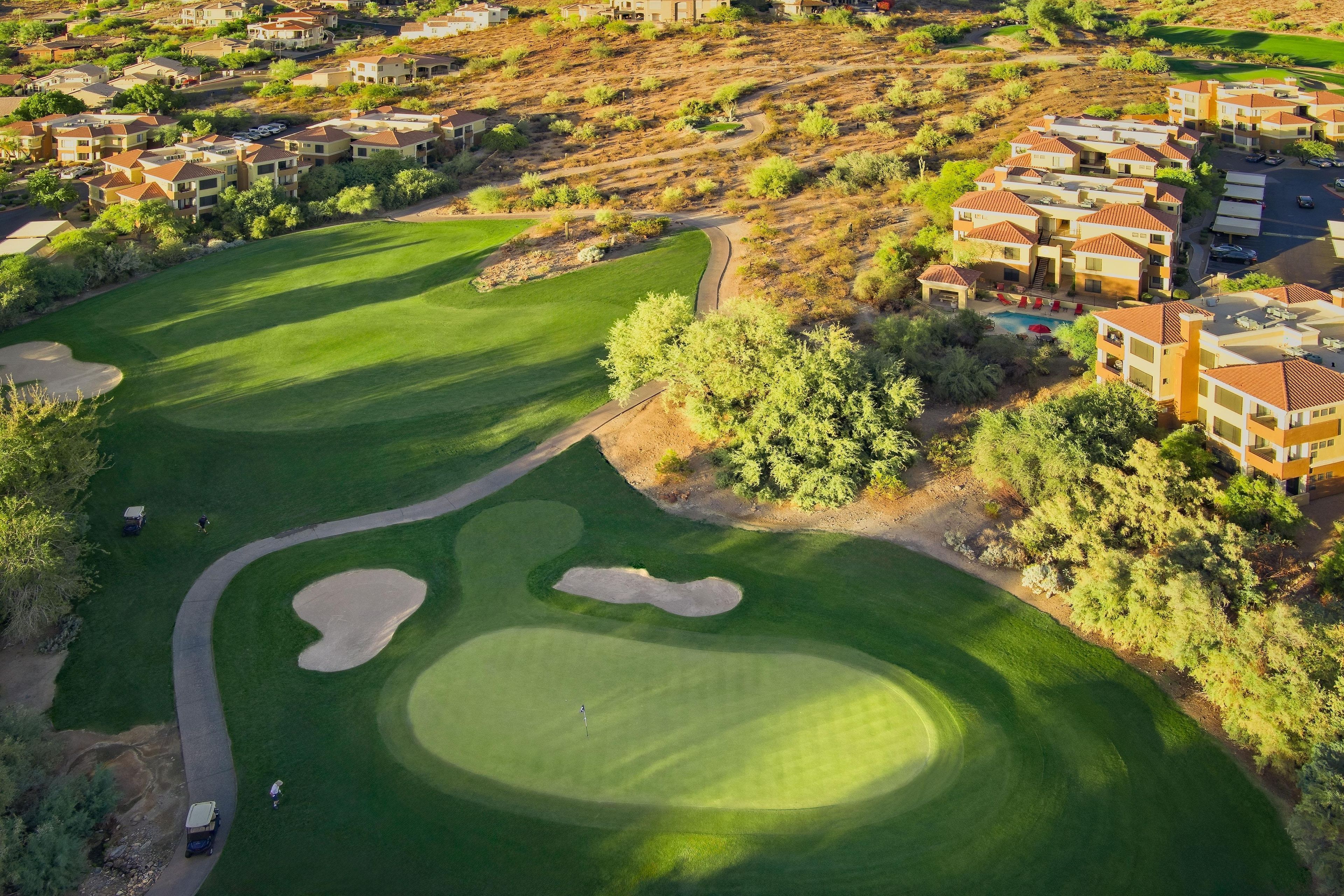 A golf course with a well-maintained fairway, sand bunkers, and a putting green.