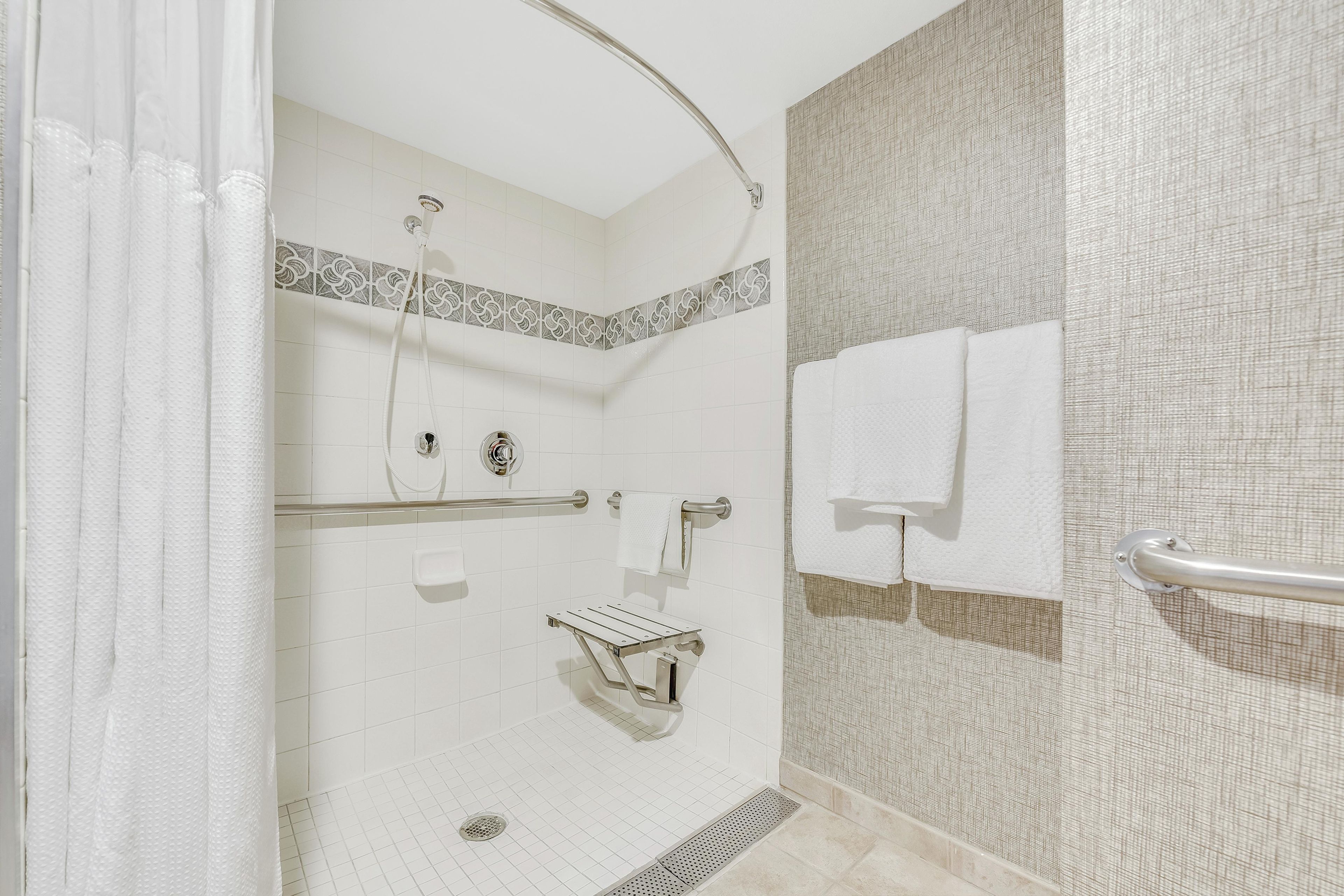 Dusche mit Duschbrause, Haltegriff und Handtuchhalter.