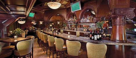 A bar area with wooden furniture, a bar counter, and a television screen.