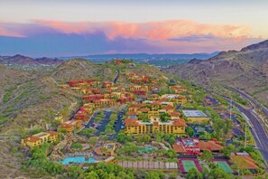 An aerial view of a resort with multiple buildings, roads, and a swimming pool.