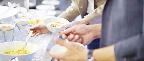 A buffet setup with multiple bowls of food on a table.