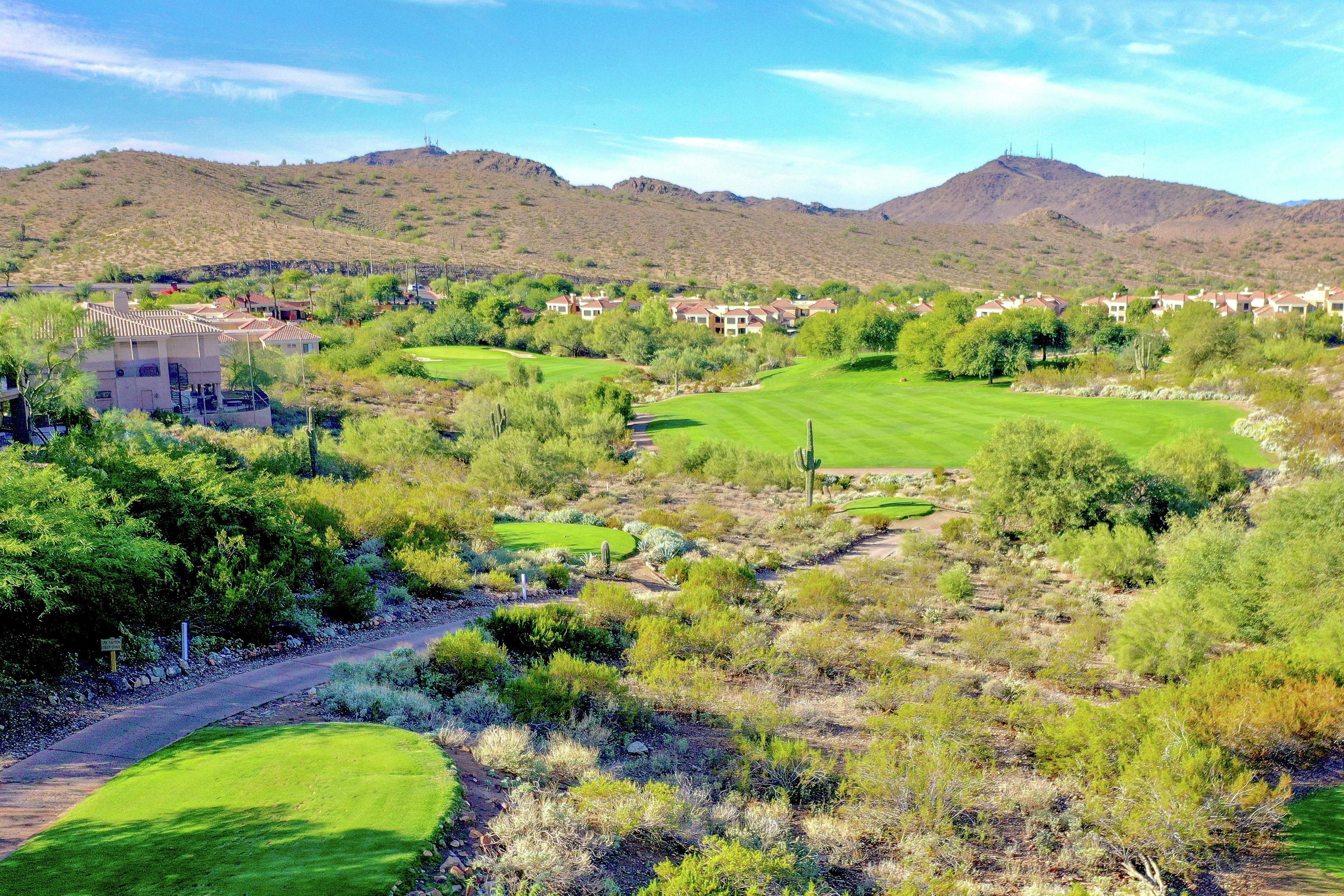 A residential area with houses, a golf course, and hilly terrain.