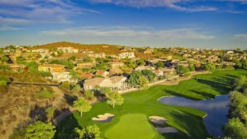 En golfbane med en sø, omgivet af bolighuse.