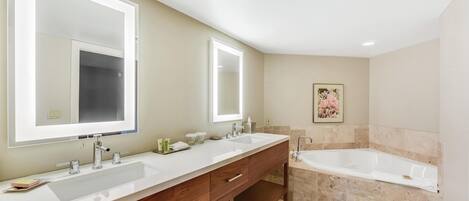 A bathroom with two sinks, a large bathtub, and a mirror above each sink.