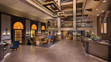 A spacious lobby with a high ceiling, multiple seating areas, and a registration desk.