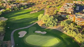 A golf course with sand bunkers, a putting green, and a clubhouse.