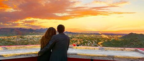 A couple overlooking a cityscape with mountains in the distance.