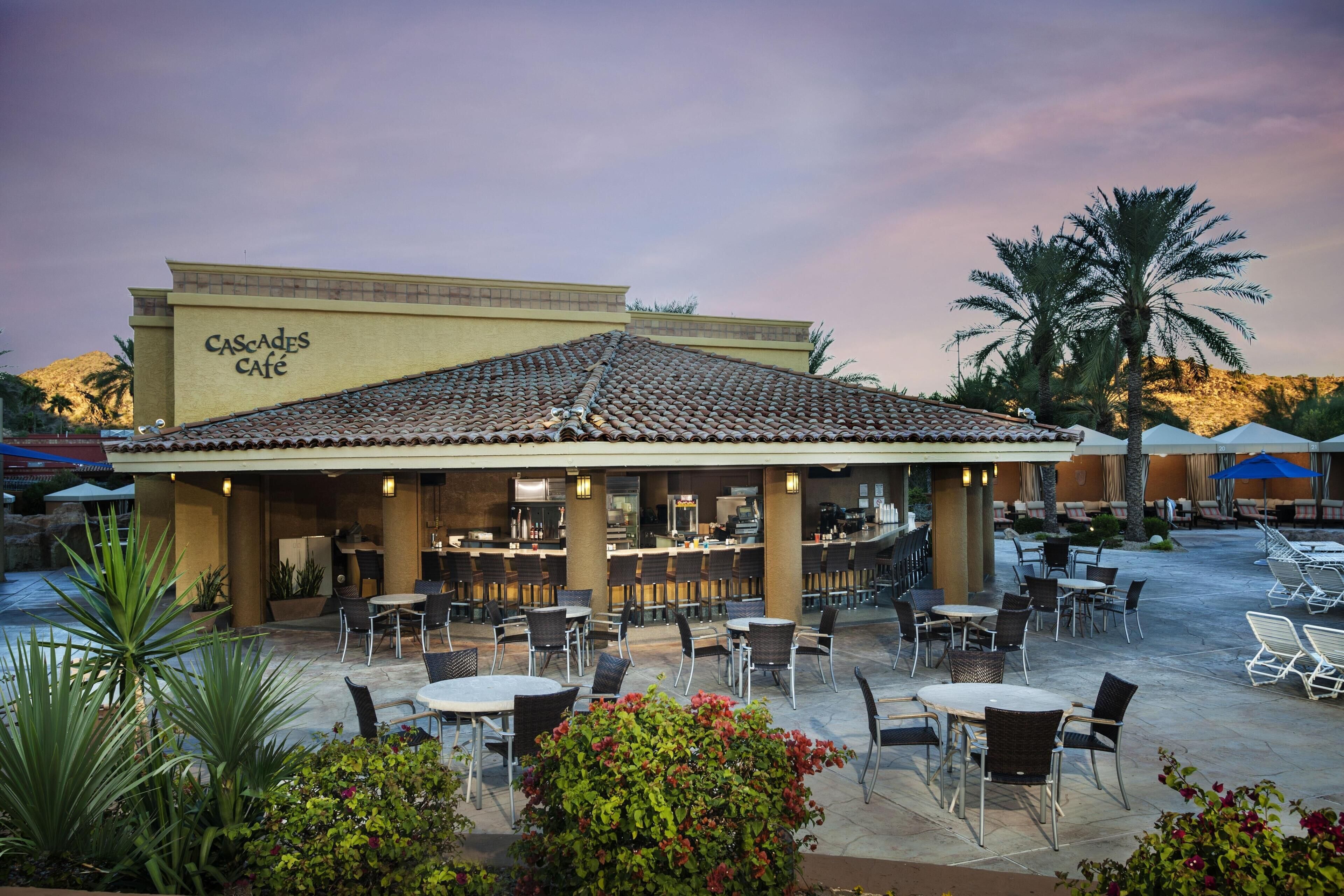 A café with outdoor seating, a tiled roof, and a sign reading 'CASCADES CAFE'.