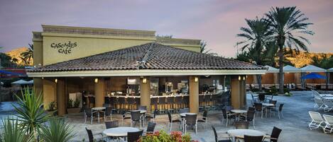 A café with outdoor seating, a tiled roof, and a sign reading 'CASCADES CAFE'.
