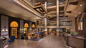 A spacious lobby with a reception desk, seating areas, and a high ceiling with decorative lighting.