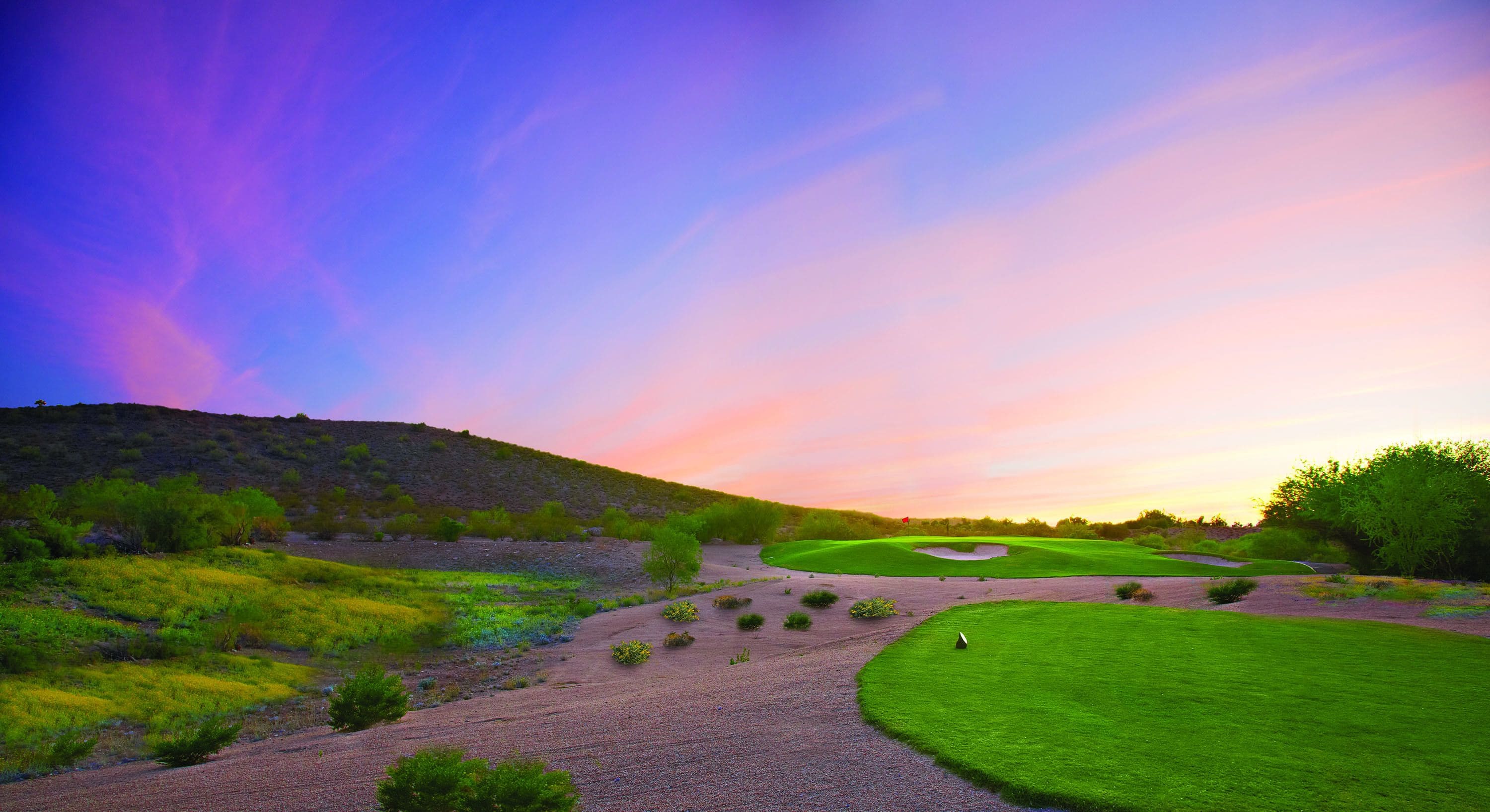 Un campo de golf con cielo despejado y atardecer.