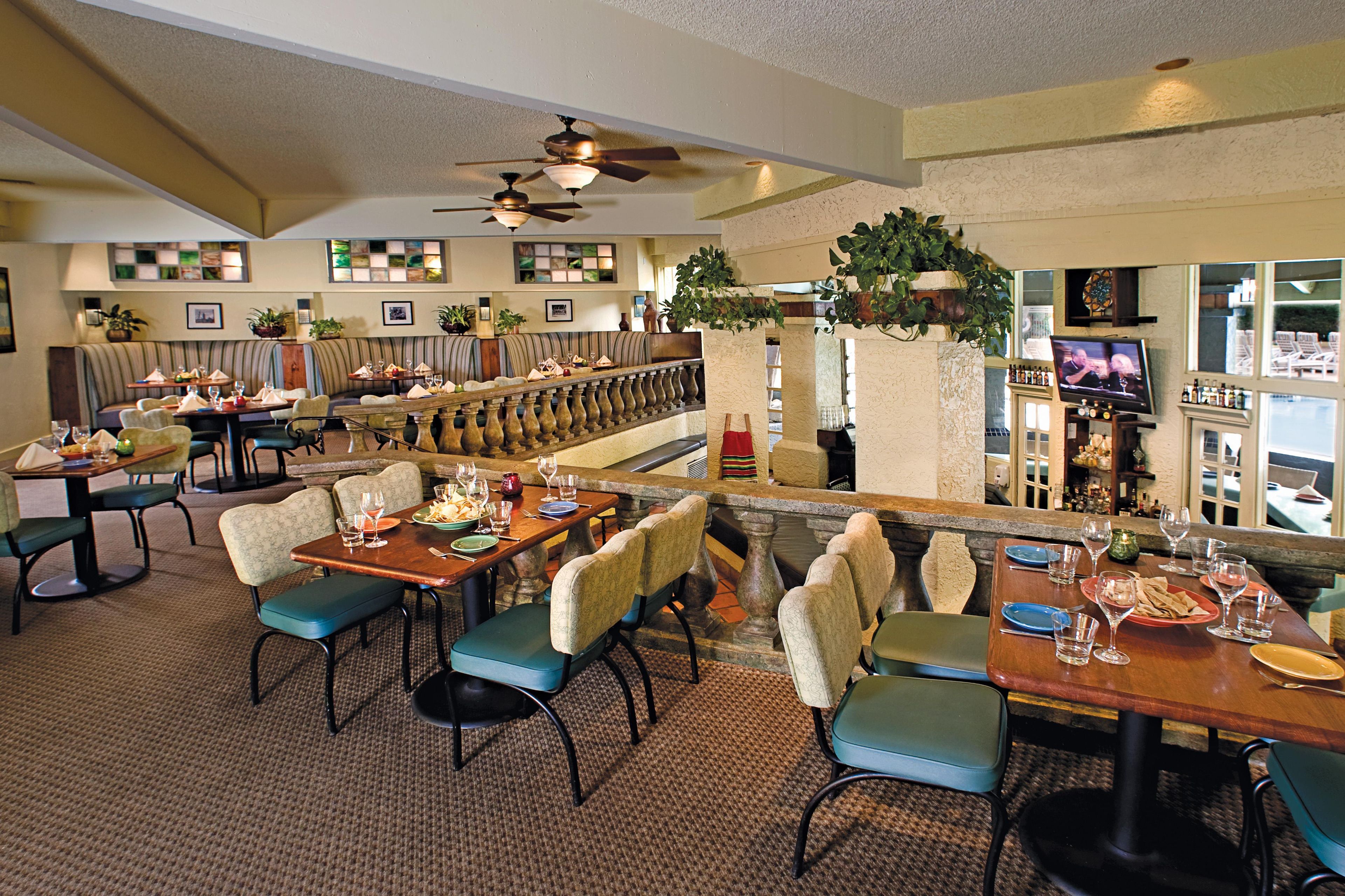 A restaurant with multiple dining tables, chairs, and a bar area.