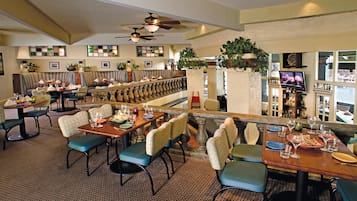 A restaurant with multiple dining tables, chairs, and a bar area.