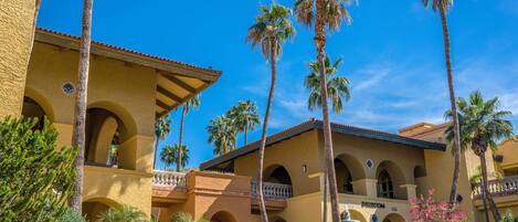 A hotel with a courtyard, palm trees, and a fountain.