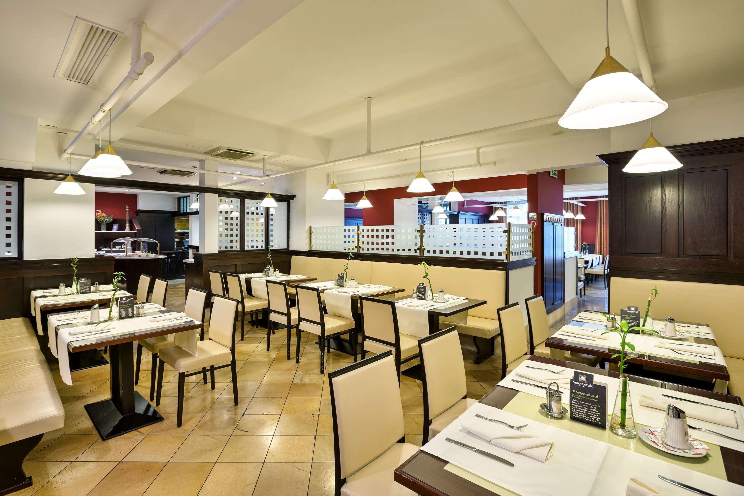 A restaurant with multiple tables and chairs, some with plants and menus.