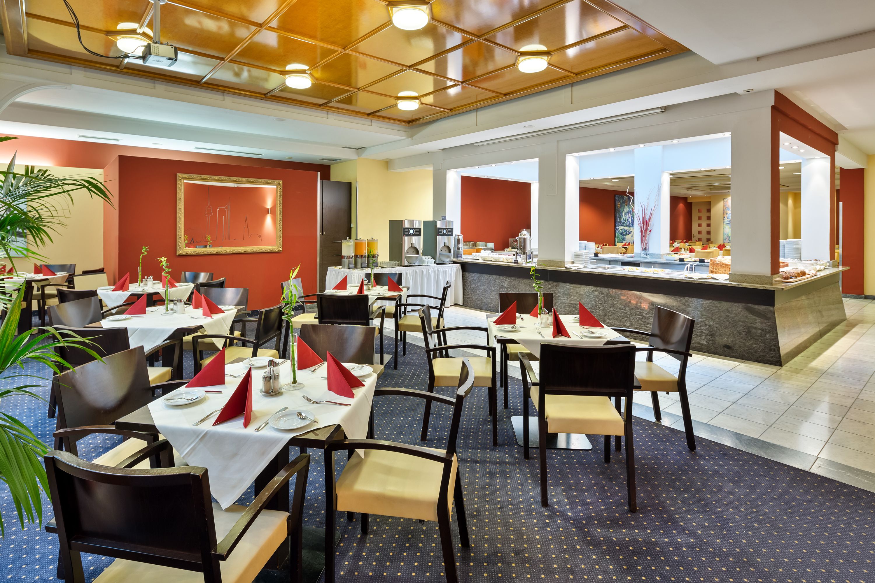 A hotel dining area with tables set for guests, a buffet counter, and a large painting on the wall.
