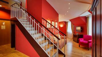 A staircase with white railings leading to a room with red walls and wooden flooring.
