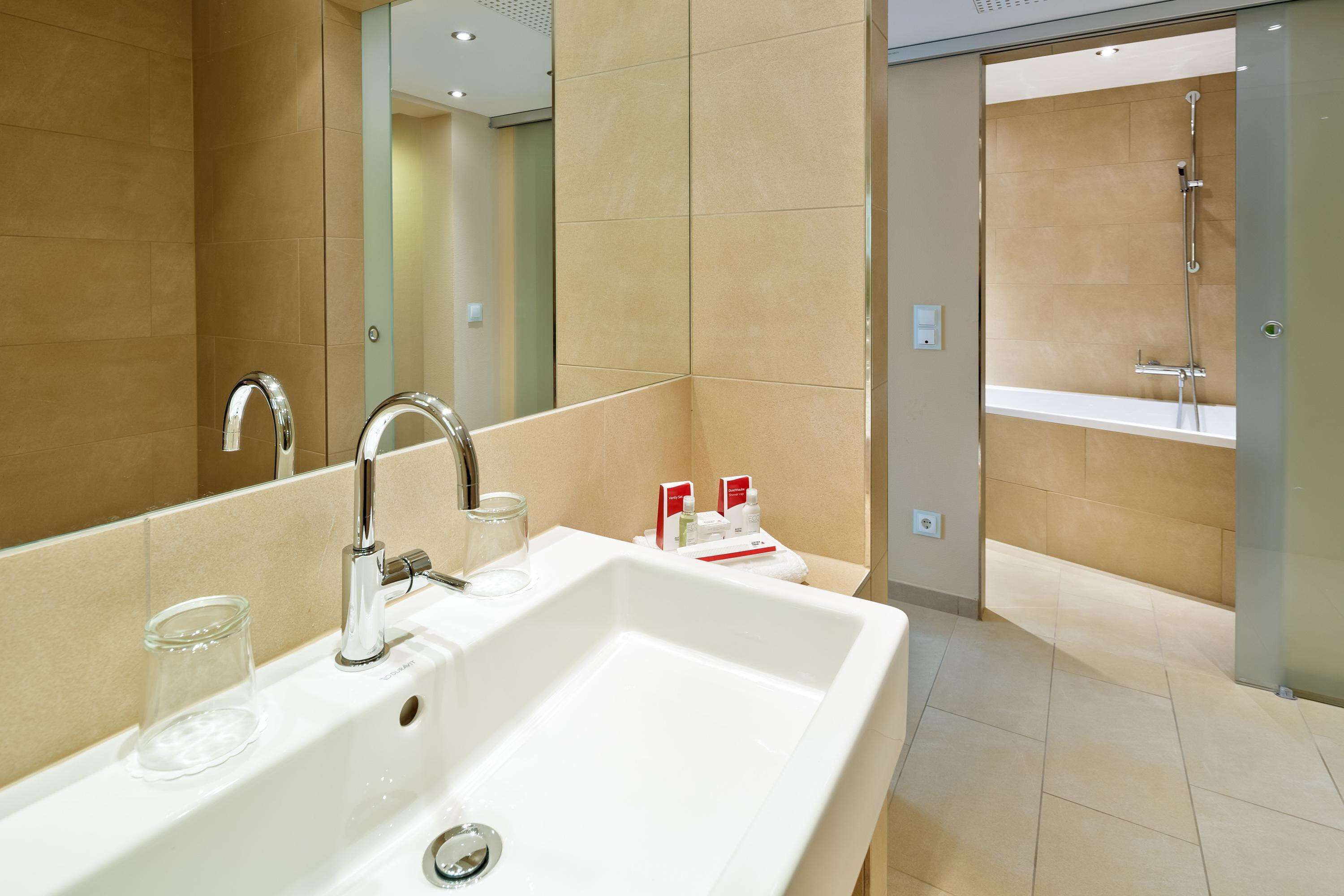 A modern bathroom with a large sink, mirror, and shower area.