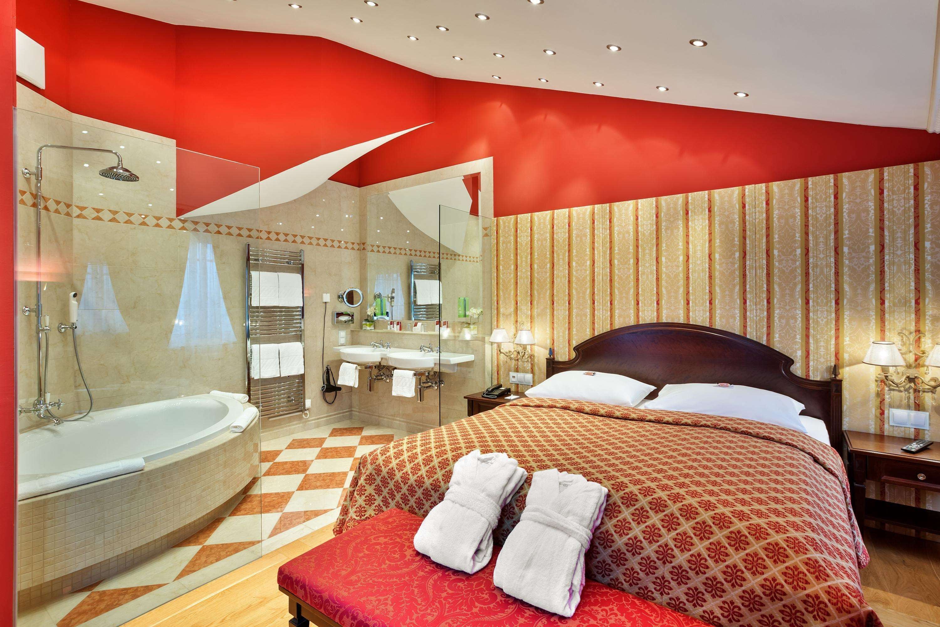 Ein Hotelzimmer mit einem großen Bett, einem separaten Badezimmer mit einer Badewanne und einem Schachbrettfußboden.