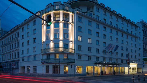 Un hotel de varios pisos con una entrada destacada en esquina, un garaje visible y un letrero que dice "Austria Trend Hotel Anasan".