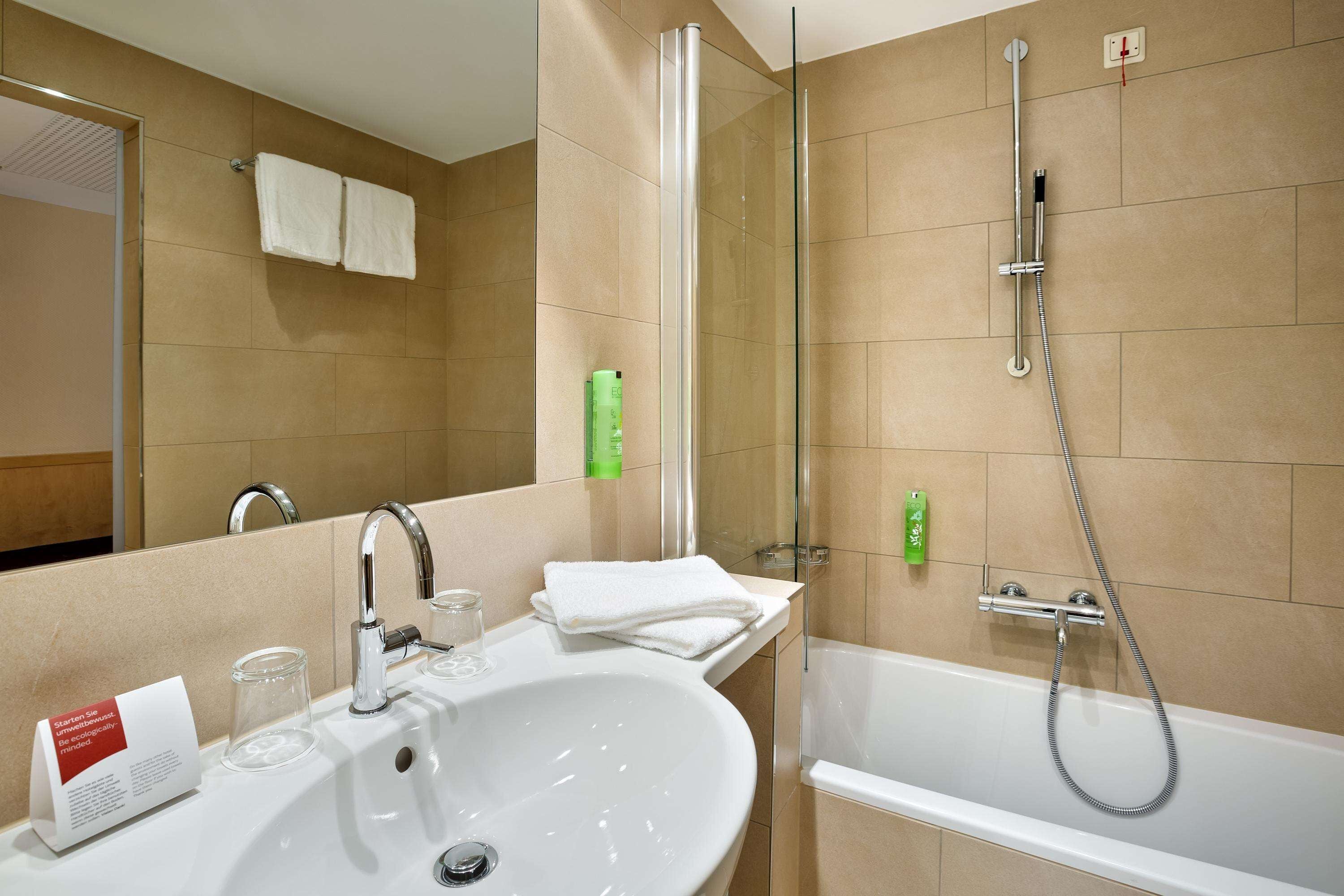 A modern bathroom with a sink, mirror, and shower.