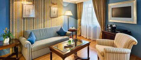 Un salon avec des canapés à rayures, une table basse en verre, un téléviseur et une lampe.