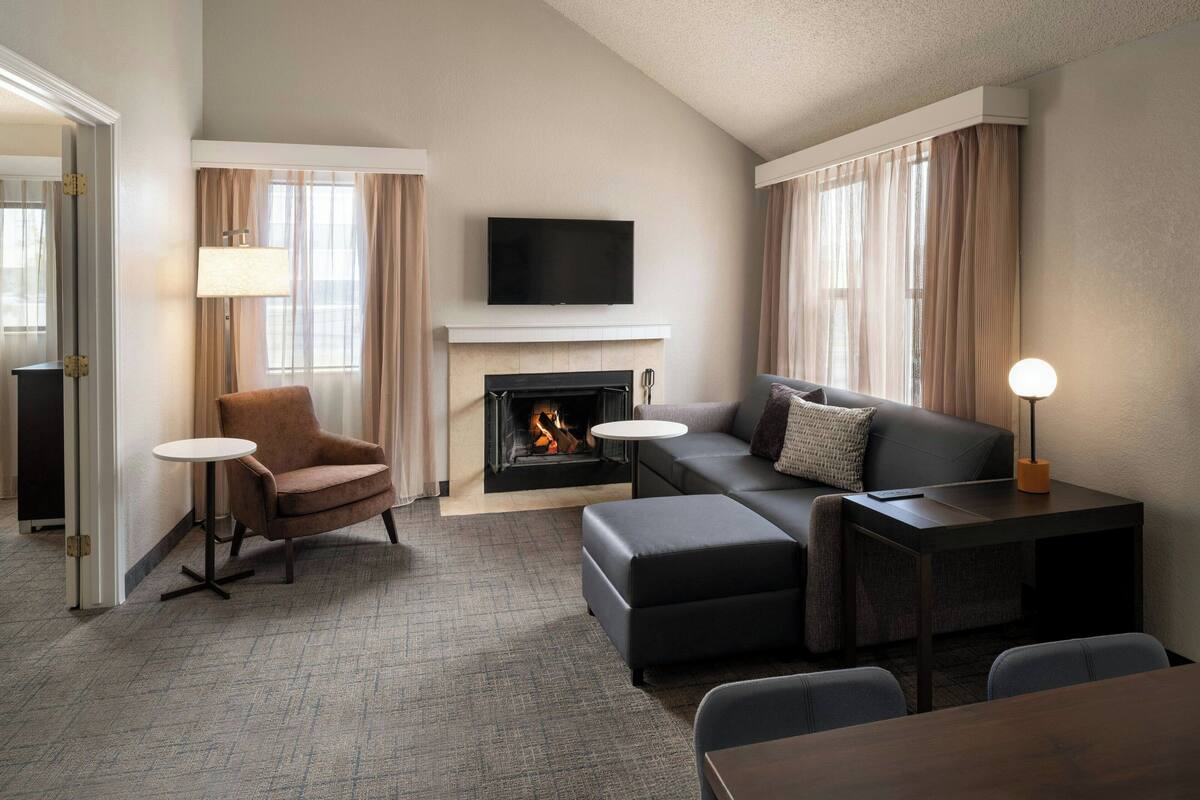 A modern living room with a fireplace, a flat-screen TV, and a sofa.